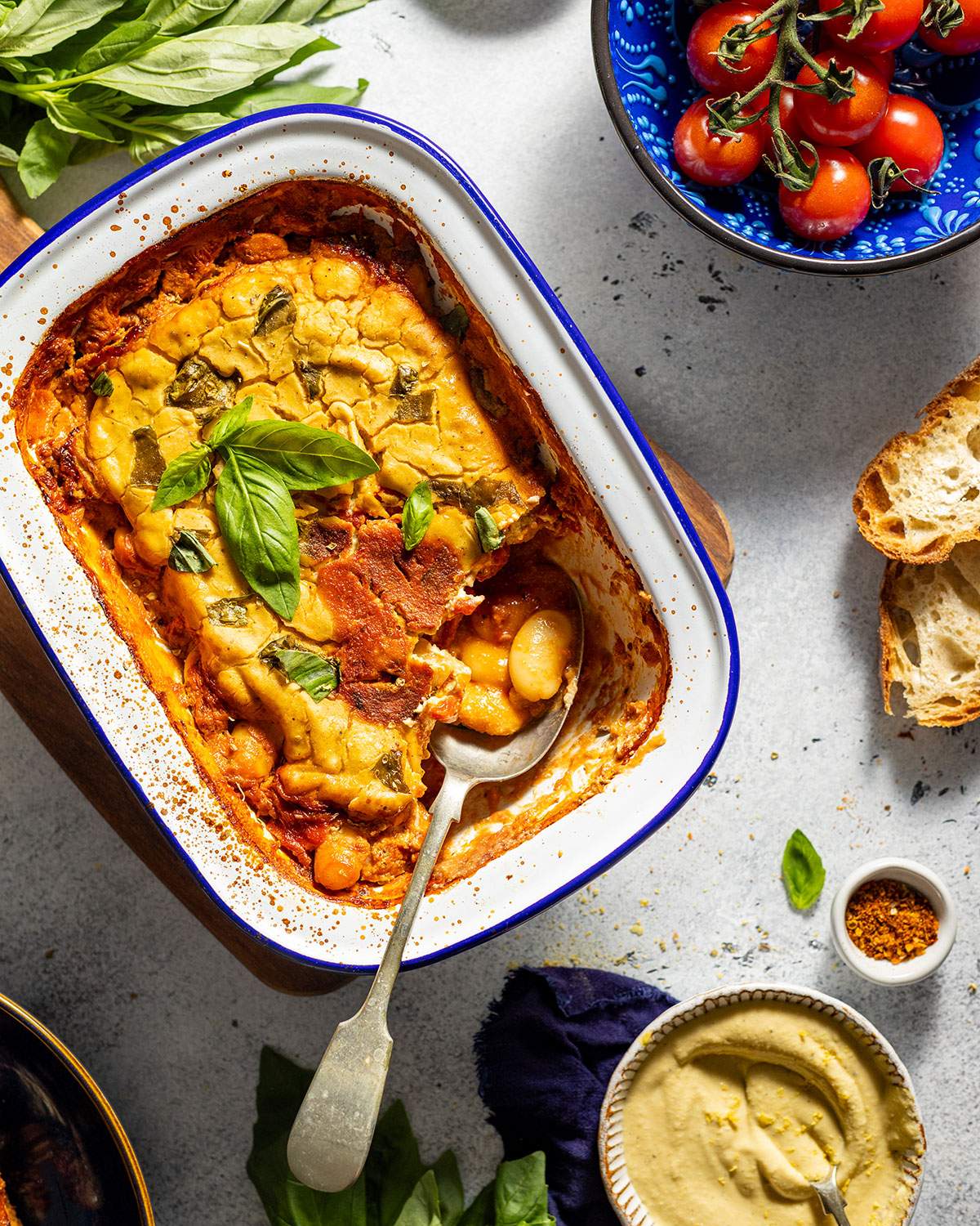Cheesy baked beans in a dish on the dinner table, with a serving spoon on the side.