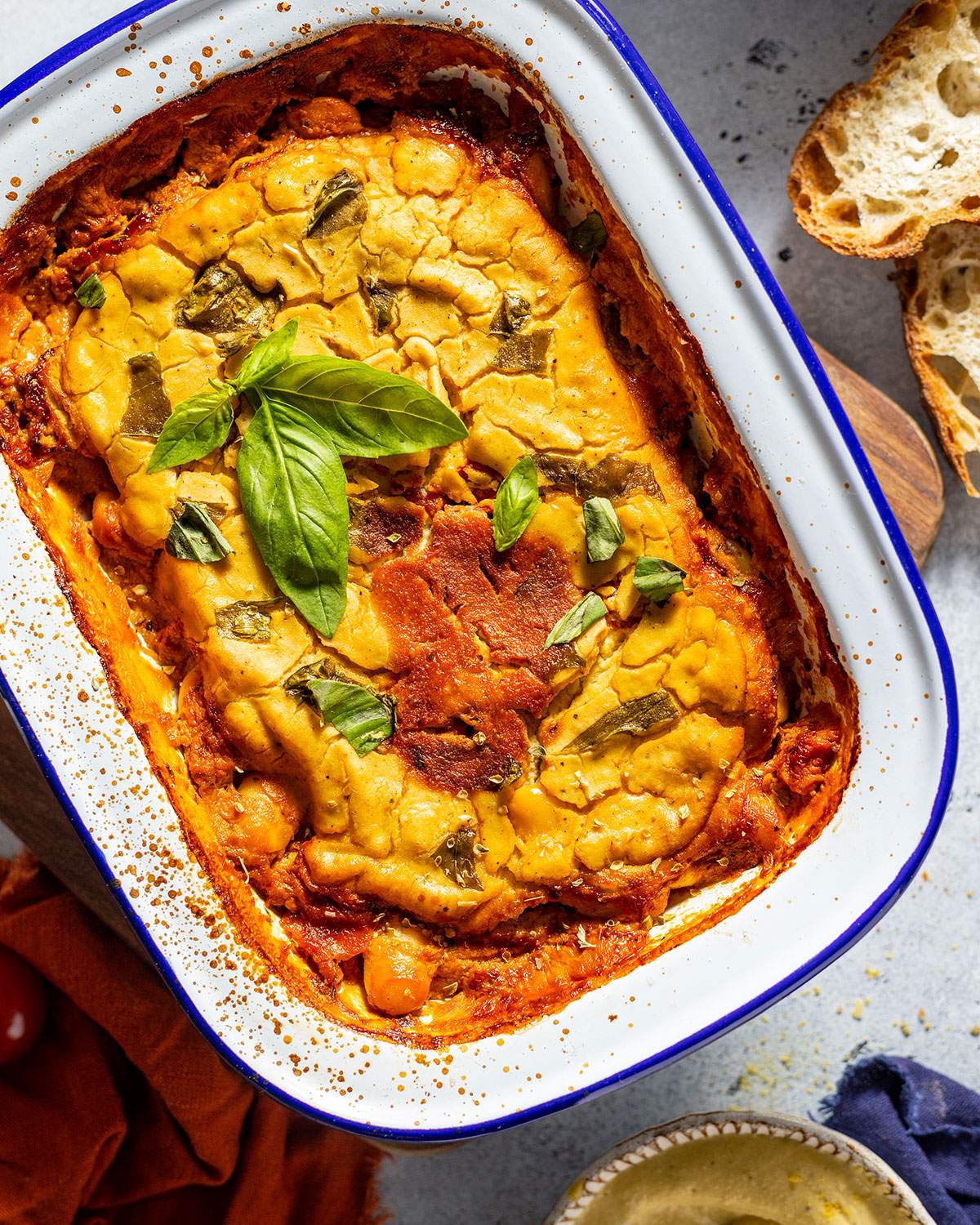 Cheesy butter beans in a baking dish, topped with fresh basil.