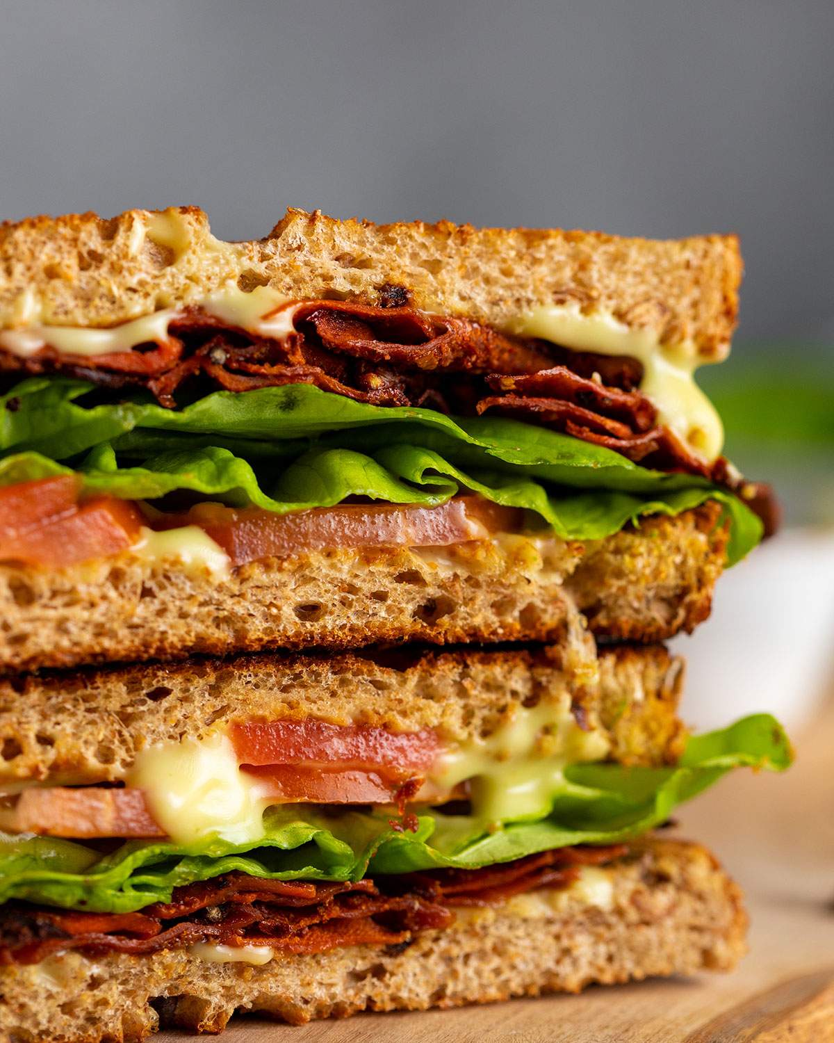 A vegan BLT sandwich up close with layers of carrot bacon, lettuce and tomato.