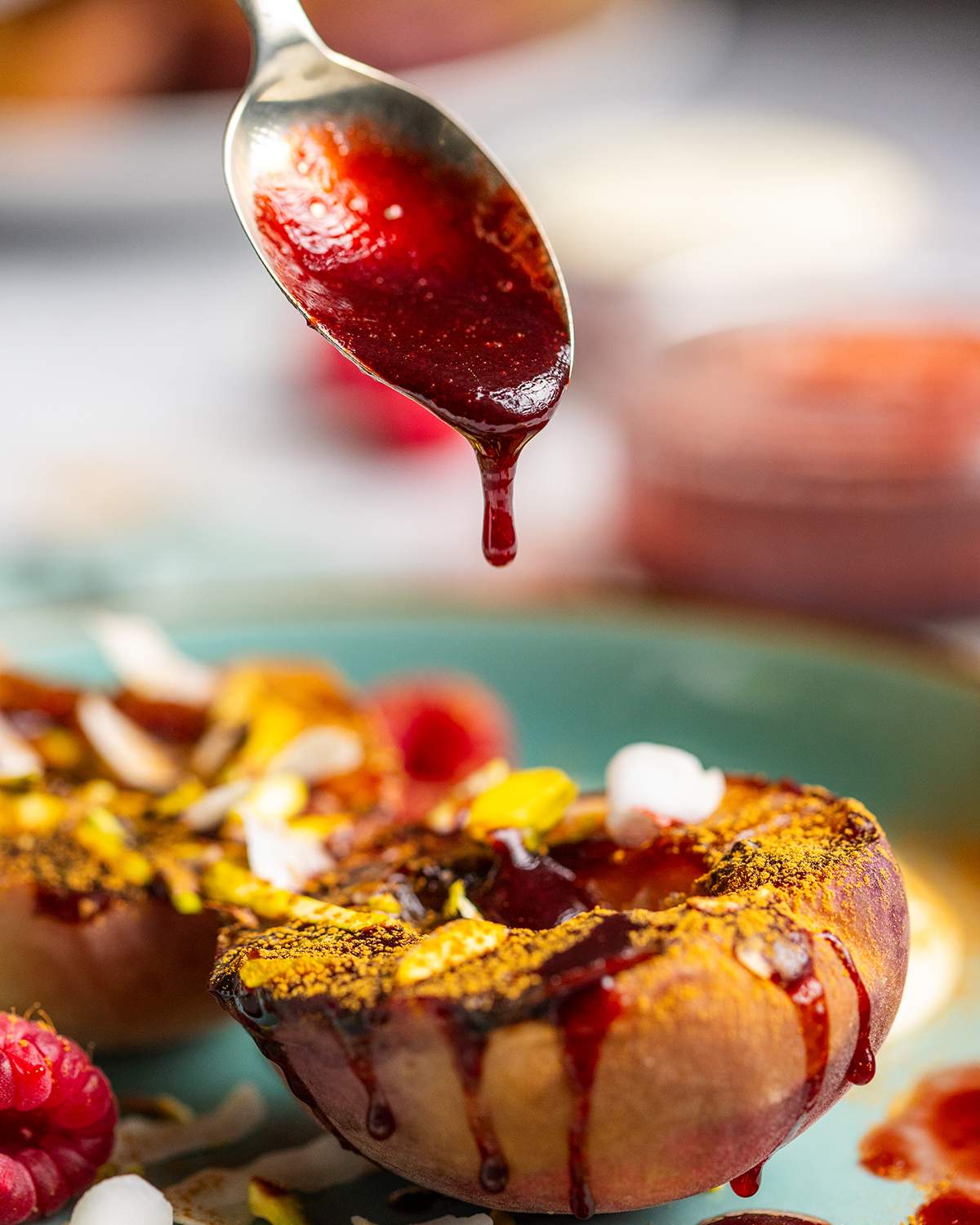 Raspberry glaze being drizzled onto grilled peaches.