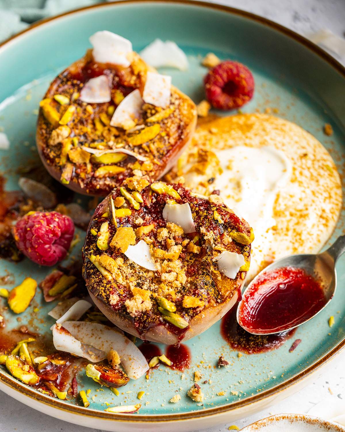 Grilled balsamic peaches with coconut yogurt and raspberry coulis on a dessert plate.