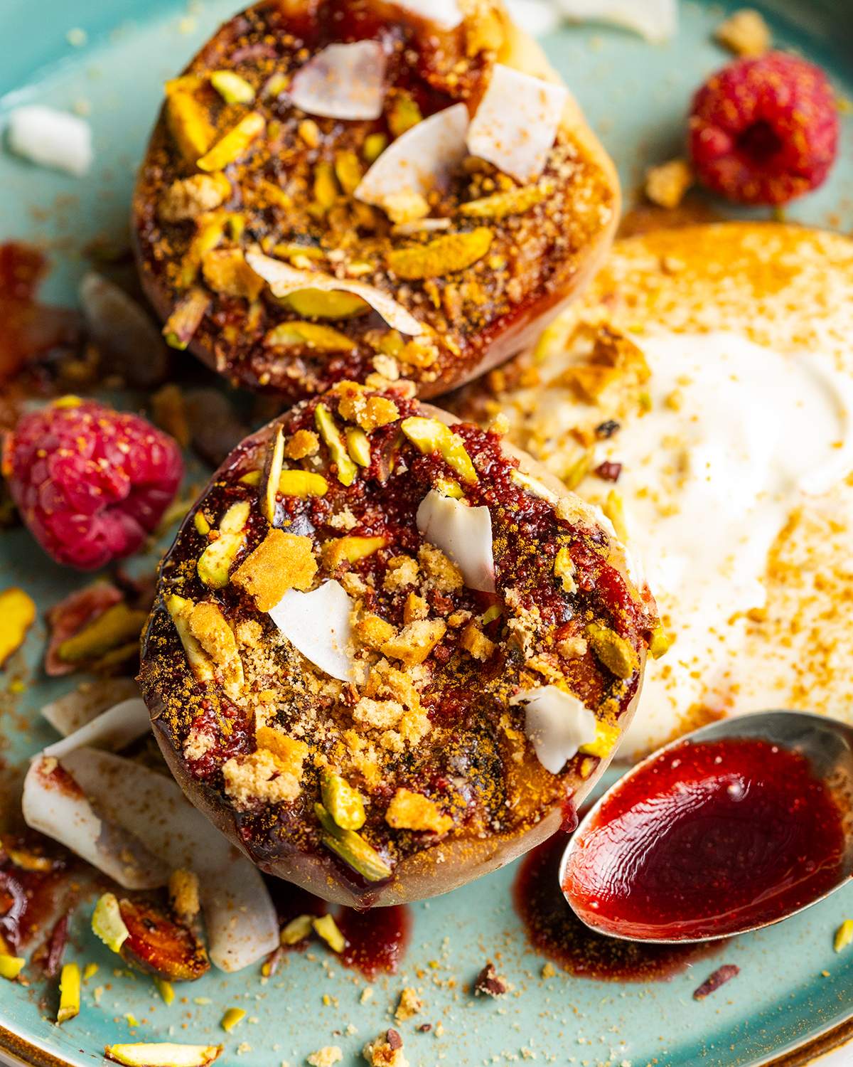 Grilled balsamic peaches with coconut yogurt and raspberry coulis on a dessert plate.