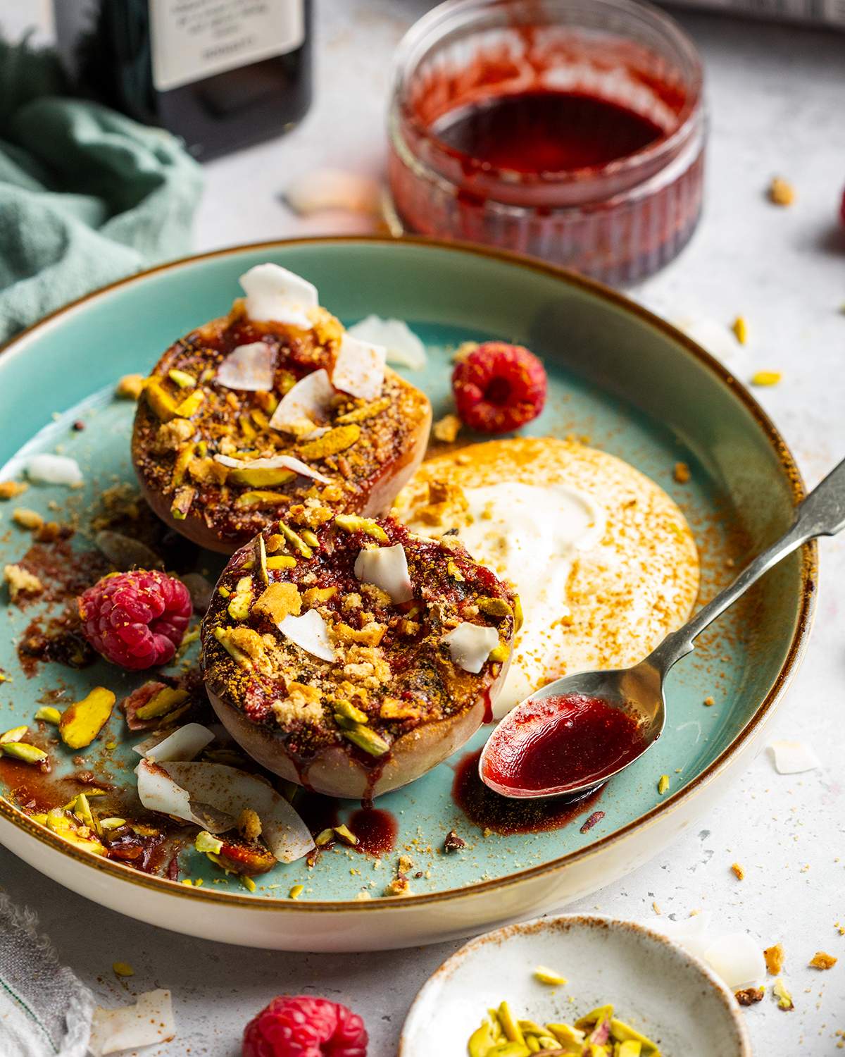 Grilled balsamic peaches with coconut yogurt and raspberry coulis on a dessert plate.