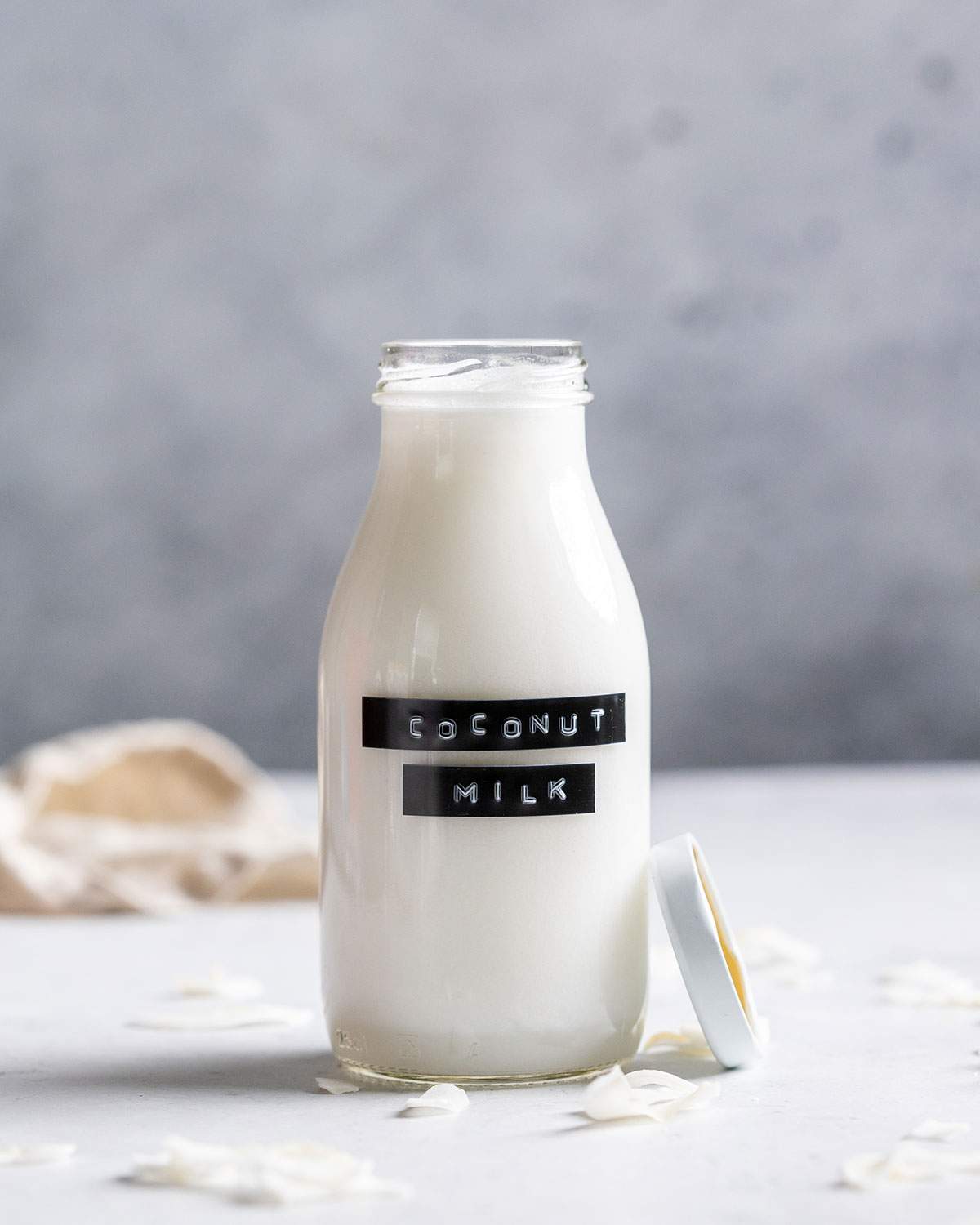 Homemade coconut milk in a glass bottle with a label.