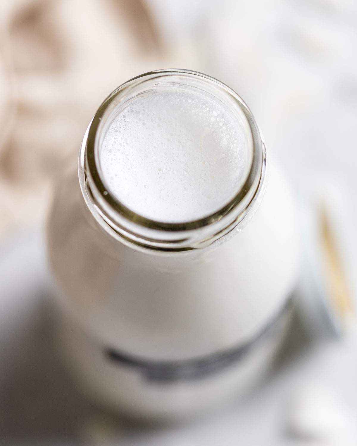 Frothy homemade coconut milk in a glass bottle.