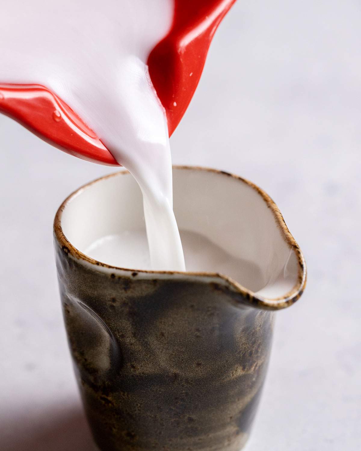 Pouring coconut cream into a jug.