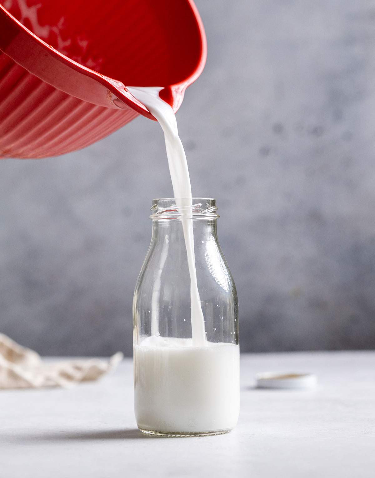 Pouring Coconut Milk into a glass bottle.