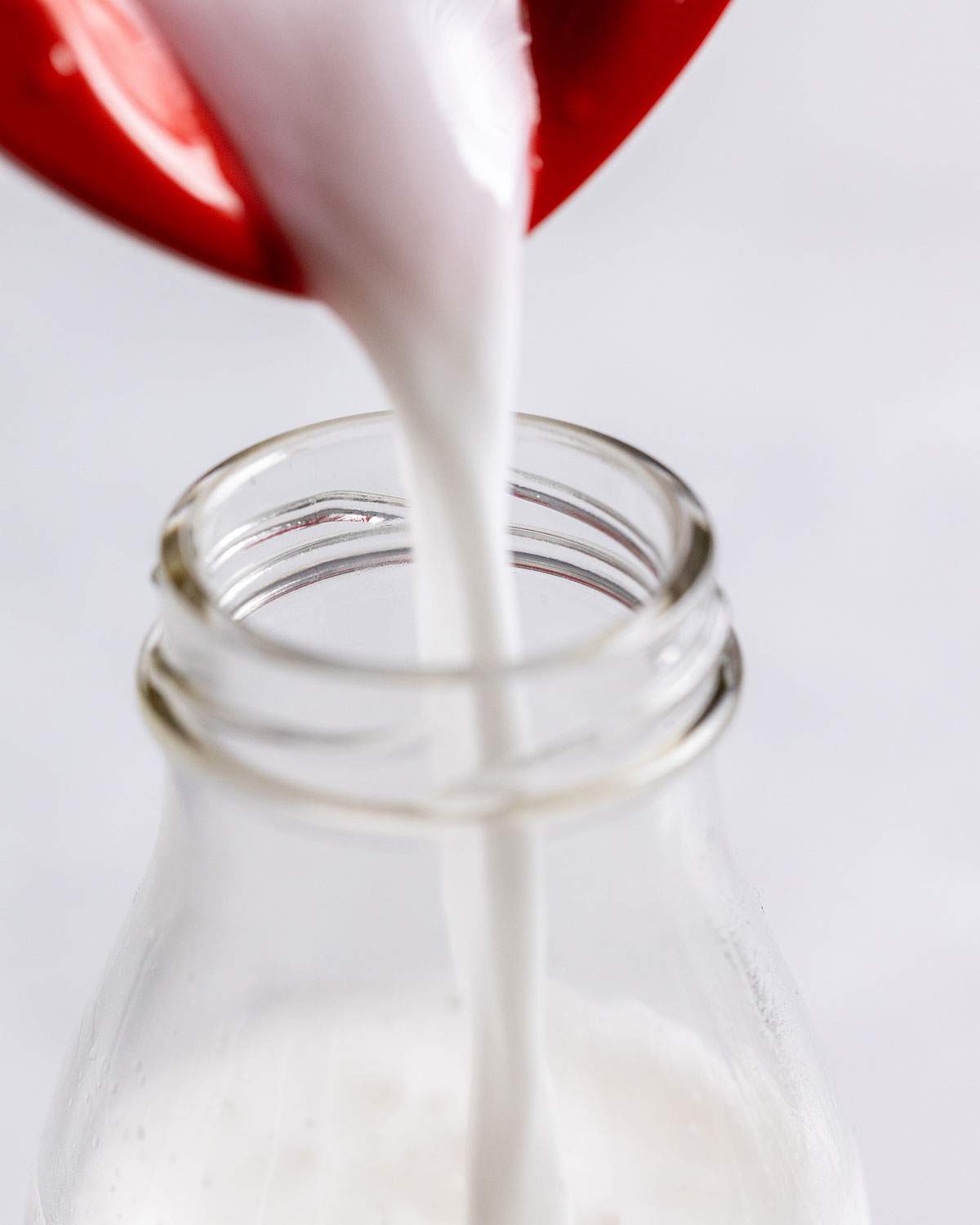 Pouring Coconut Milk into a glass bottle.