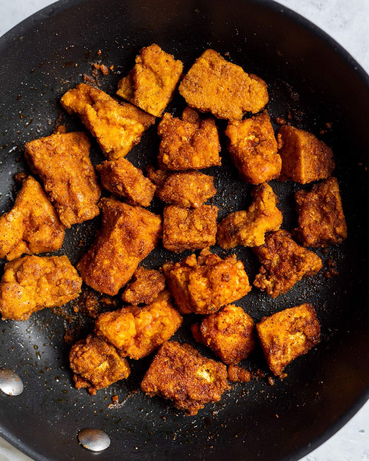 Curried tofu pieces in a skillet.