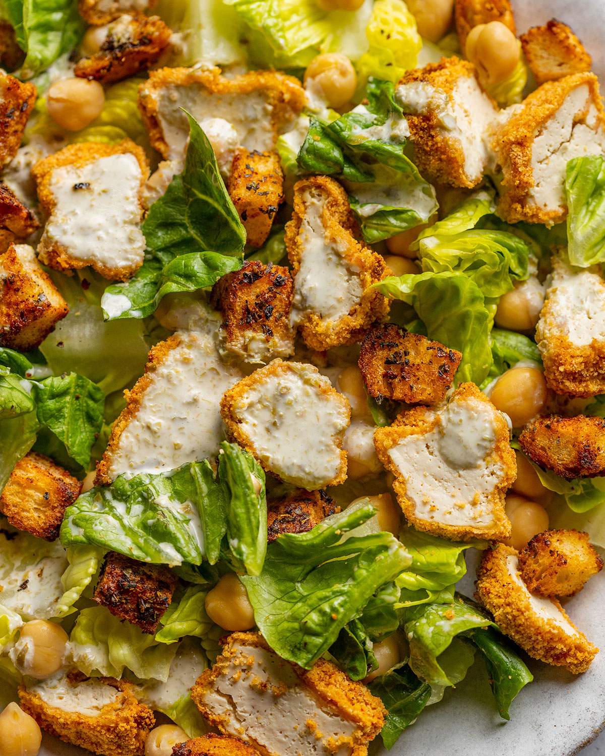Crispy tofu pieces and croutons on a salad plate.