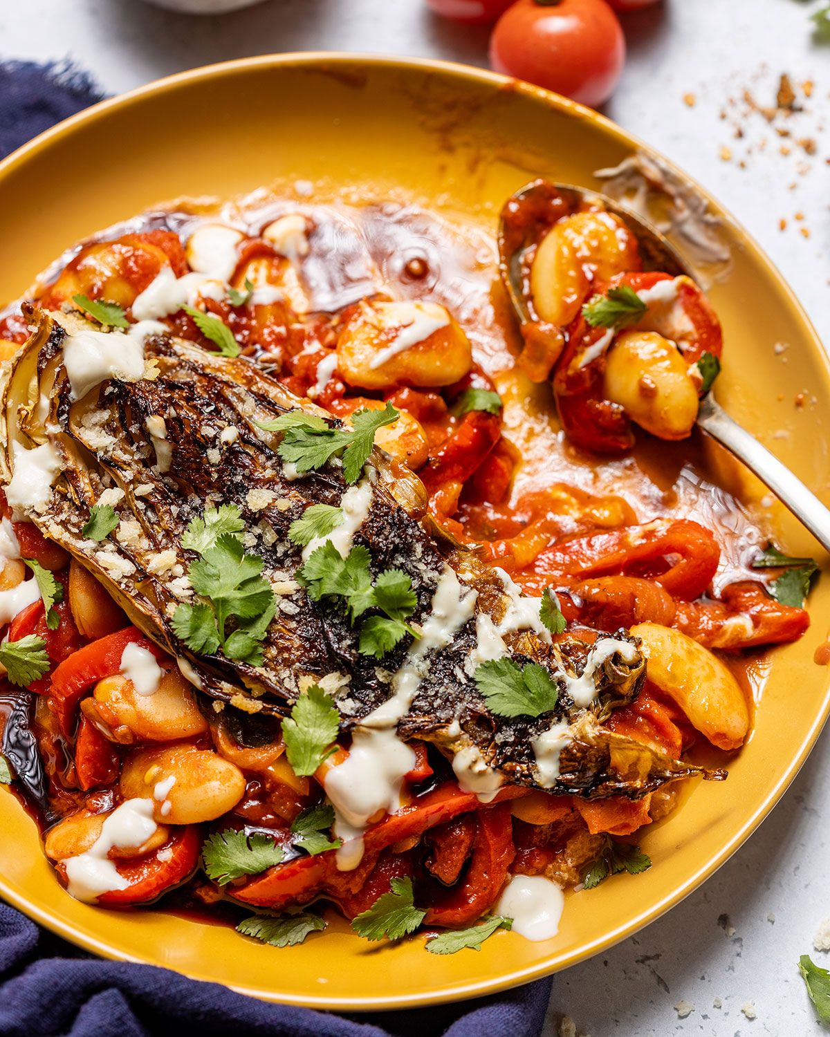 Seared cabbage and tomato butter beans on a plate with a spoon on the side.