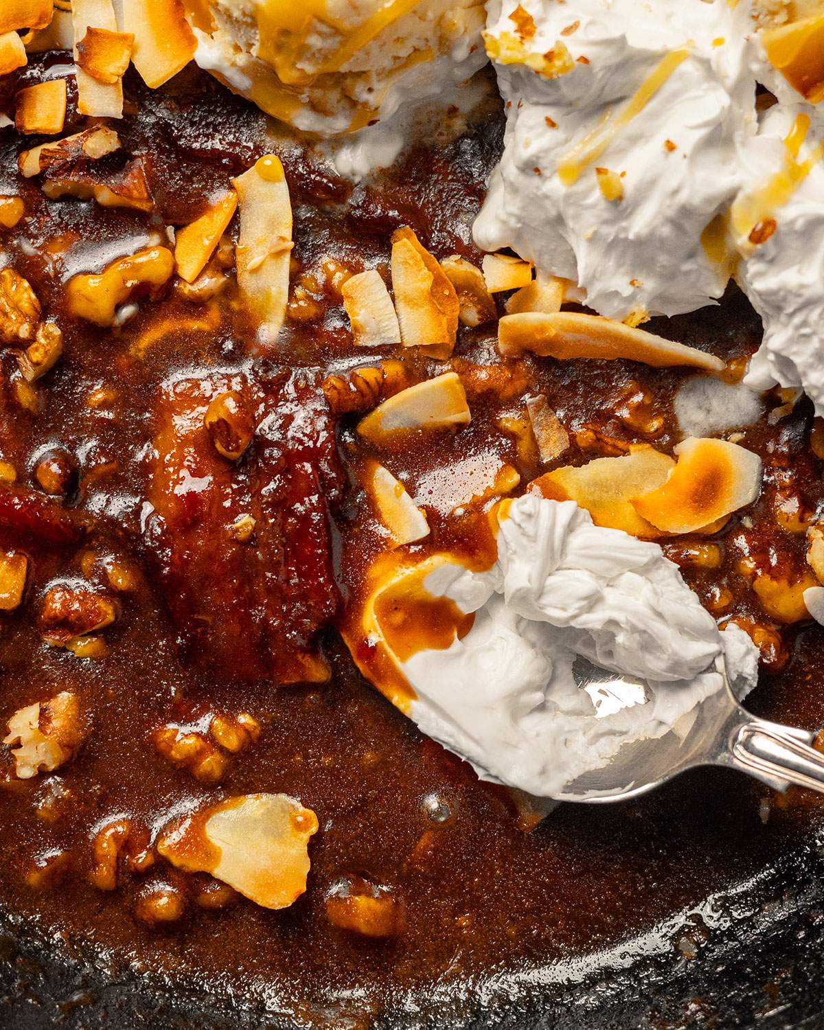 A serving spoon in a skillet with bananas foster.