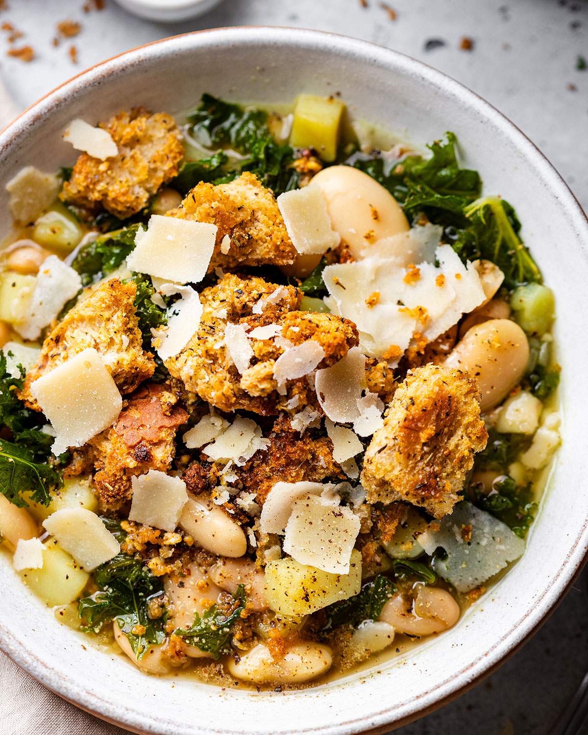Rustic butter bean and kale soup in a bowl up close.