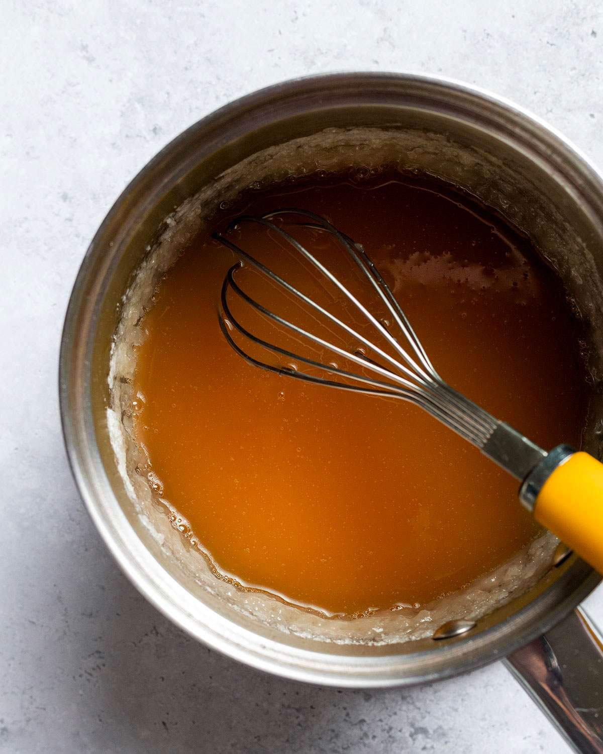 Whisking vegan caramel sauce in a saucepan.