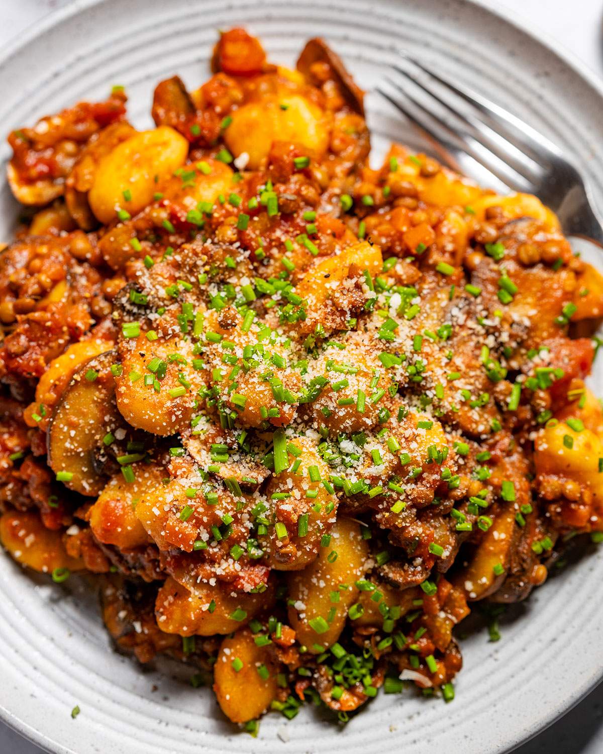 Vegan gnocchi with hearty lentil ragu on a serving plate.