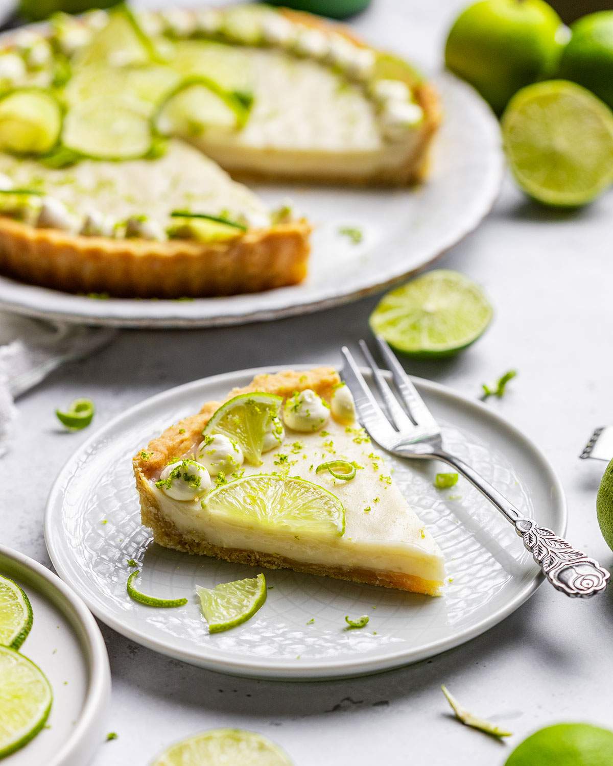 A slice of vegan key lime pie with a fork on a dessert plate.