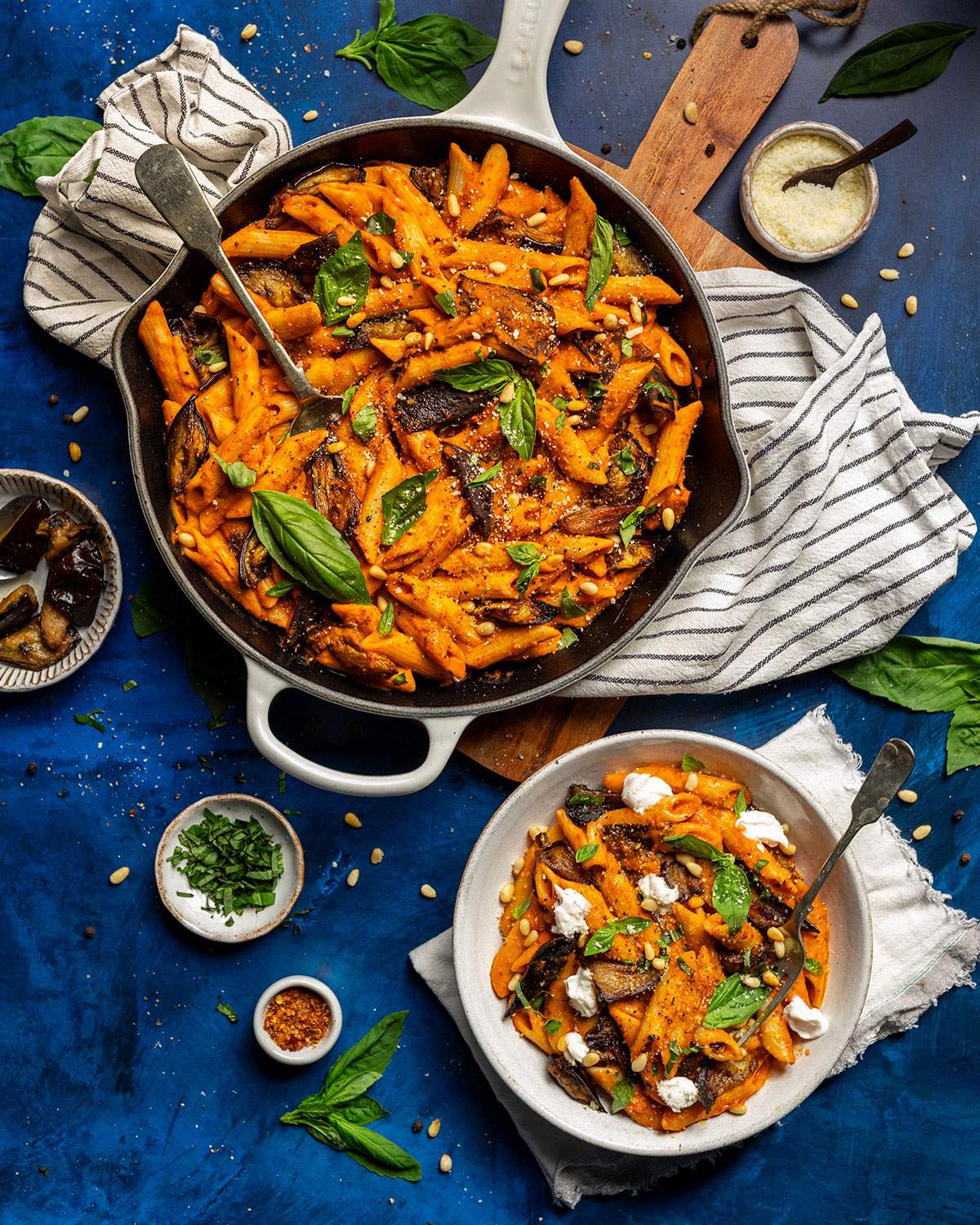 A bowl of vegan nduja pasta on the dinner table next to the skillet.