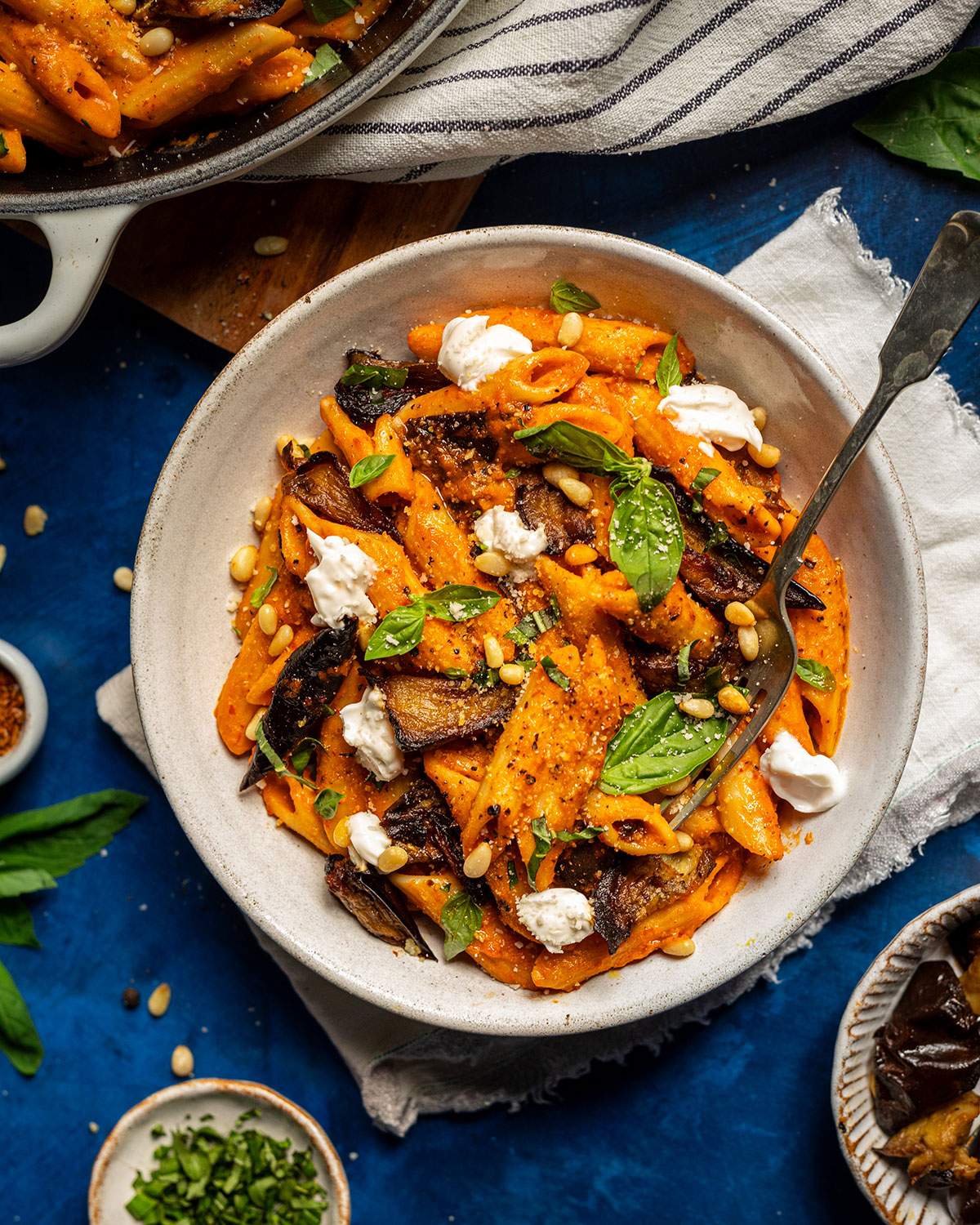 A bowl of vegan nduja pasta on the dinner table next to the skillet.
