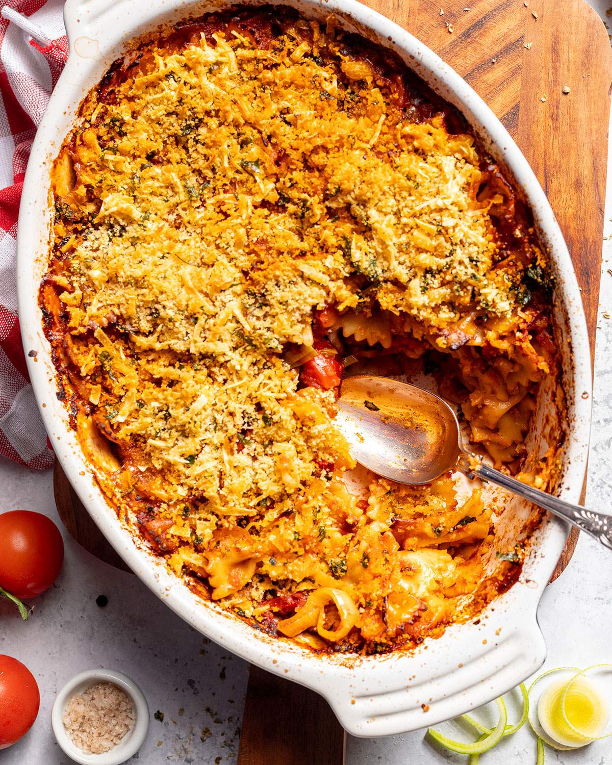 A casserole dish filled with vegan pasta bake and a serving spoon on the side.