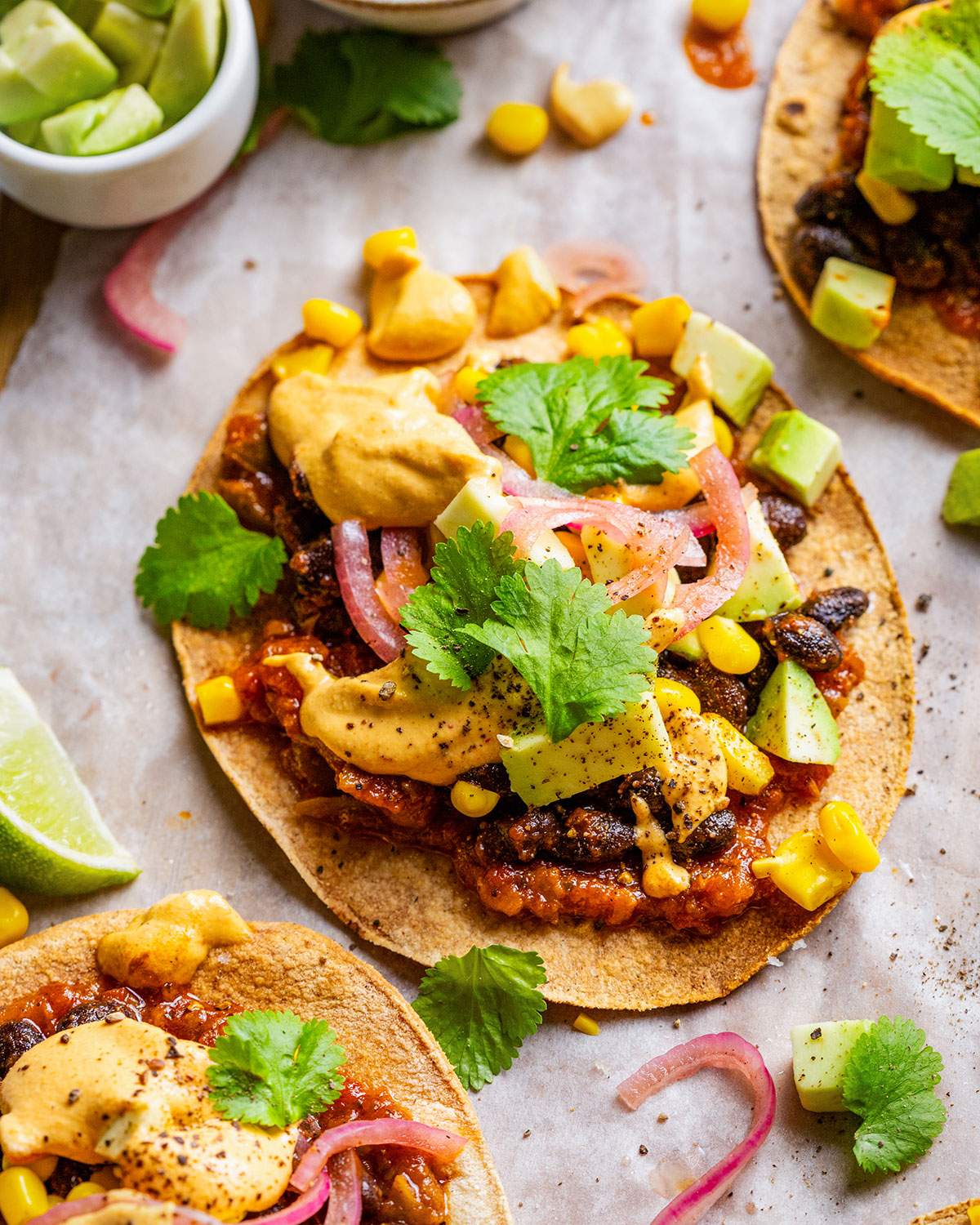 Vegan tostadas with black beans, sweetcorn, salsa, pickled onions, cilantro and vegan nacho cheese sauce.