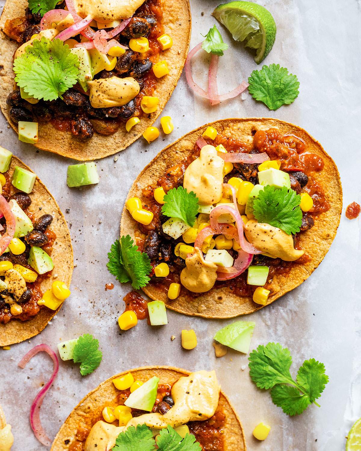 Vegan tostadas with black beans, sweetcorn, salsa, pickled onions, cilantro and vegan nacho cheese sauce.
