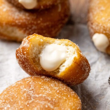 A custard donut up close with a bite taken out of it and the creamy vegan custard filling showing.