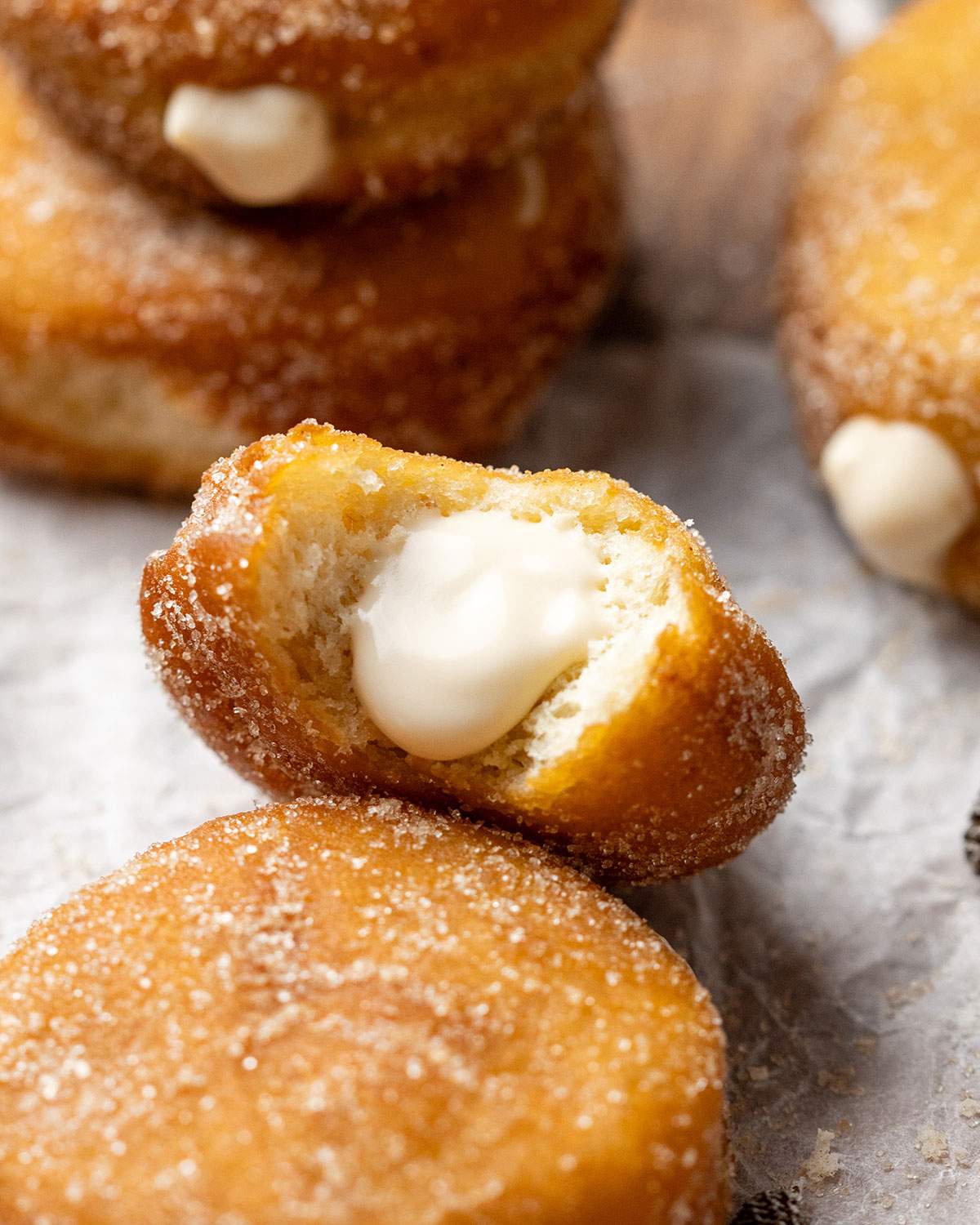 A custard donut up close with a bite taken out of it and the creamy vegan custard filling showing.