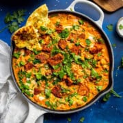 A skillet filled with creamy chickpea curry with tofu on top.