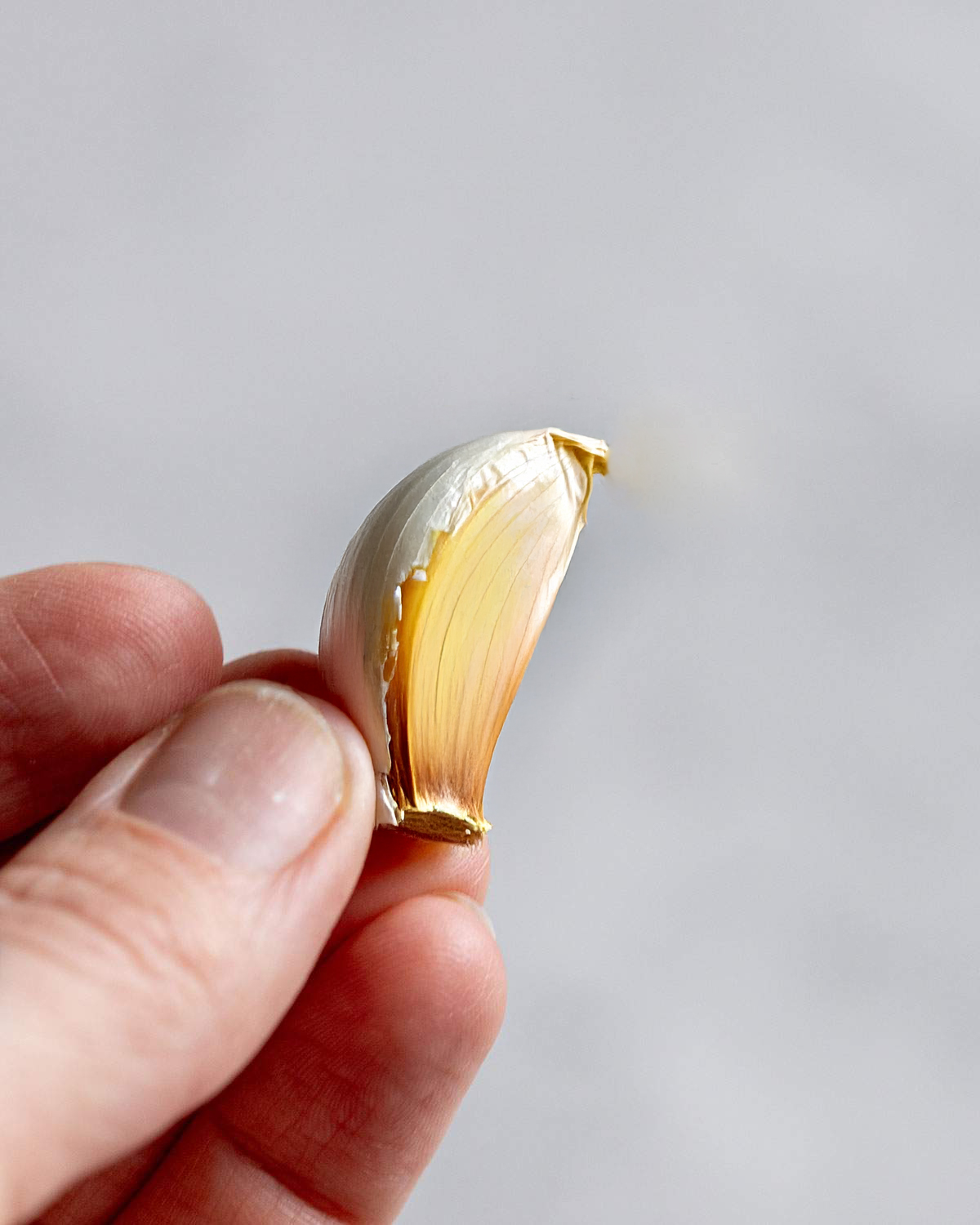 A yellowing clove of garlic in a hand.