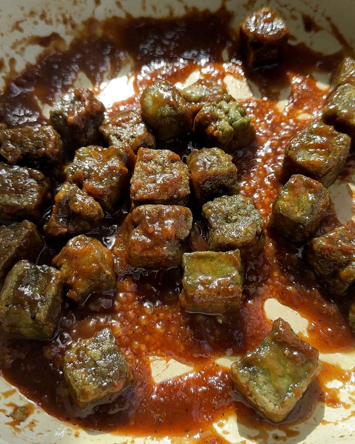 Pumpkin tofu cubes and sauce in a skillet.