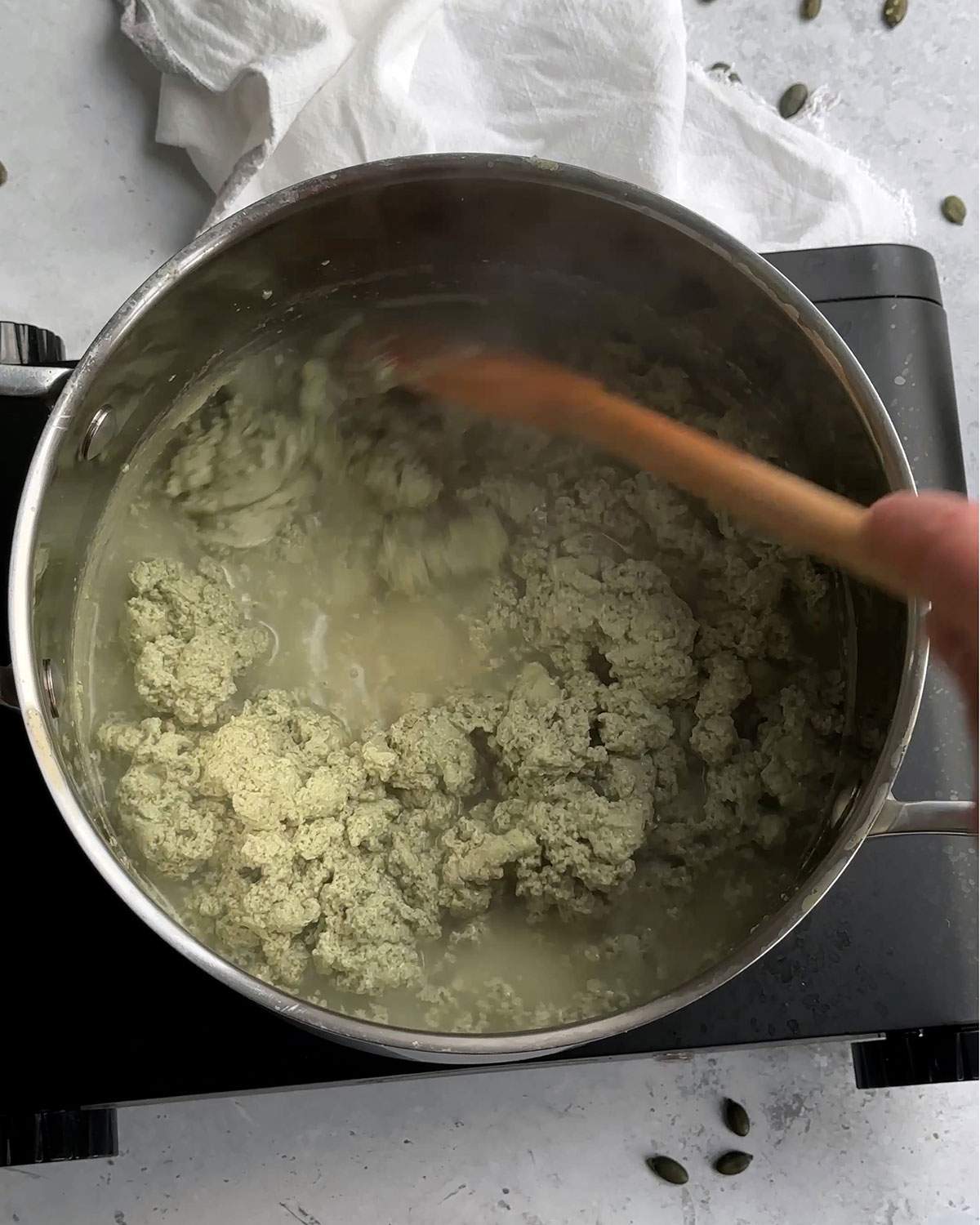 Curdled pumpkin seed milk in a saucepan.