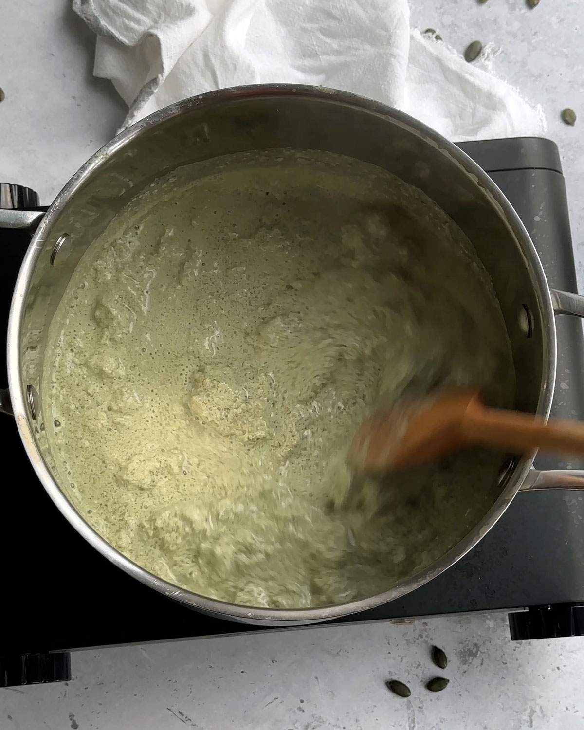 Curdling pumpkin seed milk in a saucepan.