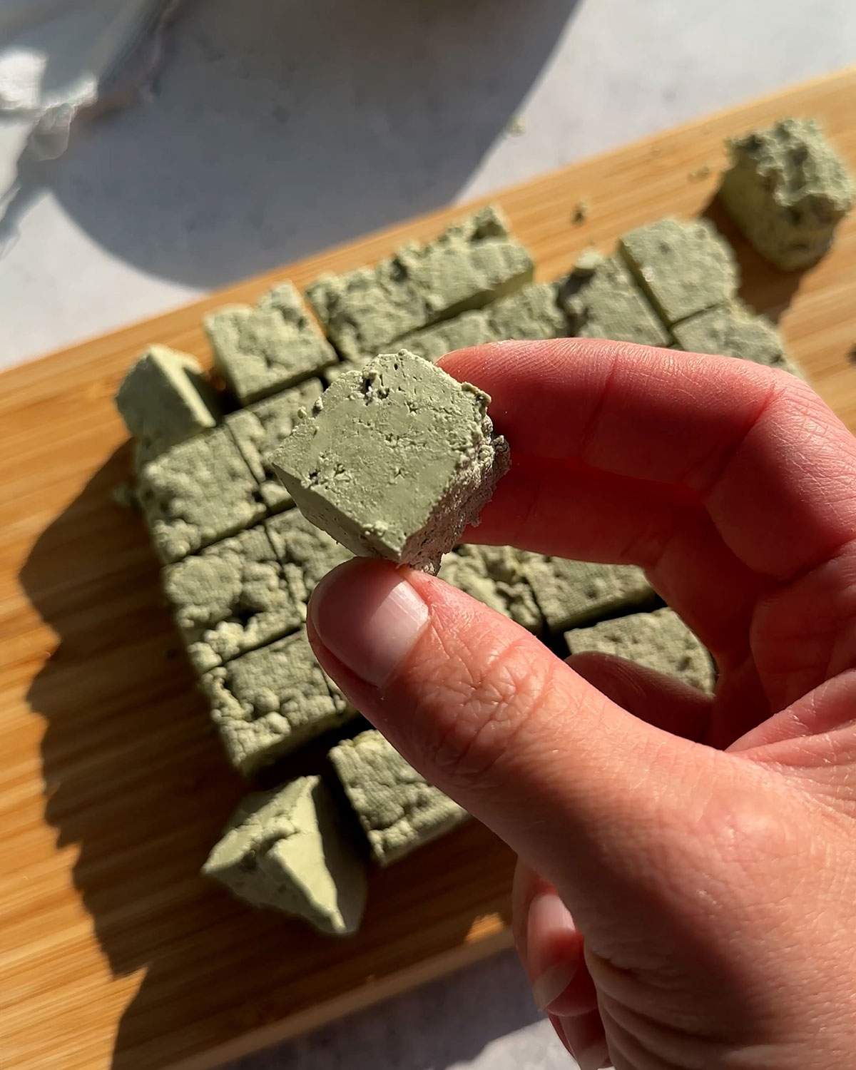 A hand holding a cube of pumfu tofu.