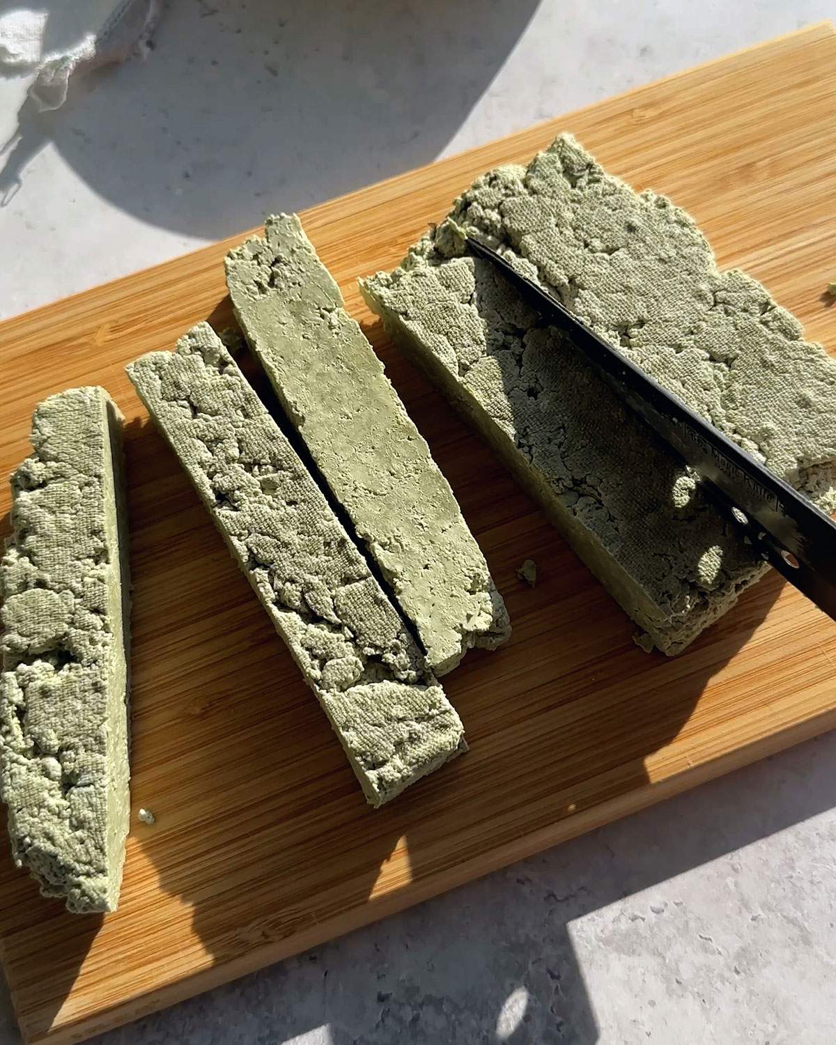 A knife cutting a block of pumfu tofu.