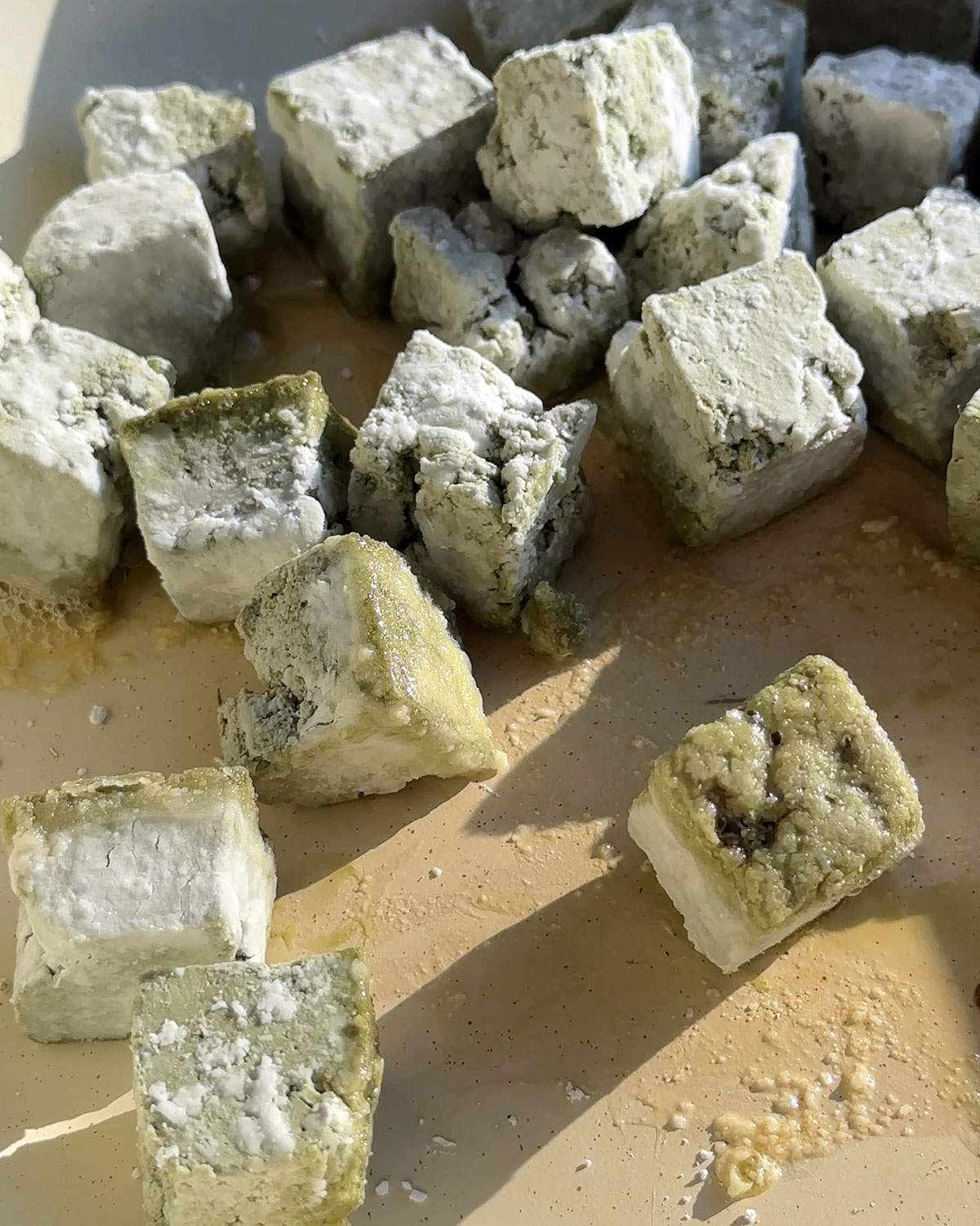 Coated Pumfu cubes frying in a pan.