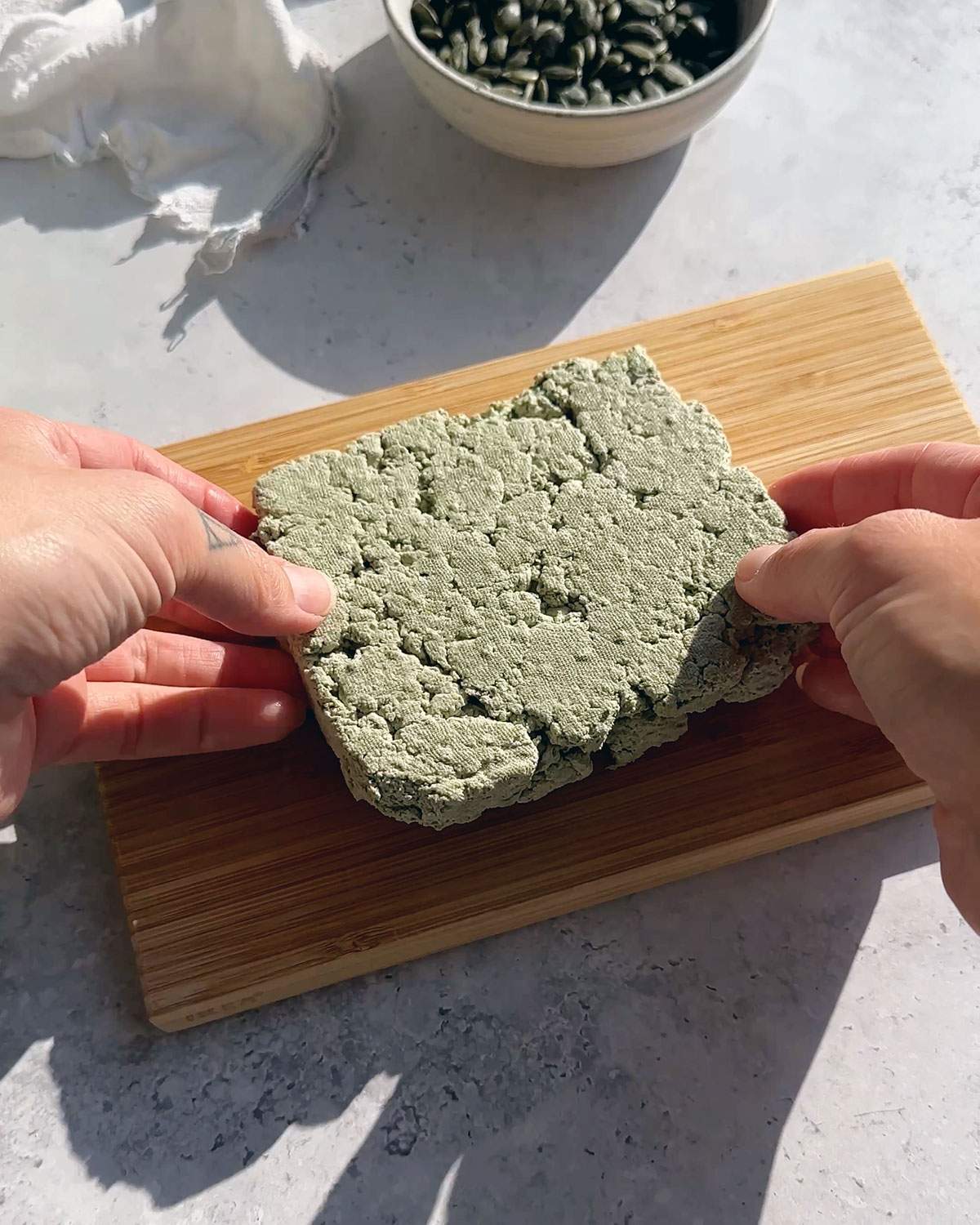 Hands holding a firm pumfu tofu block.