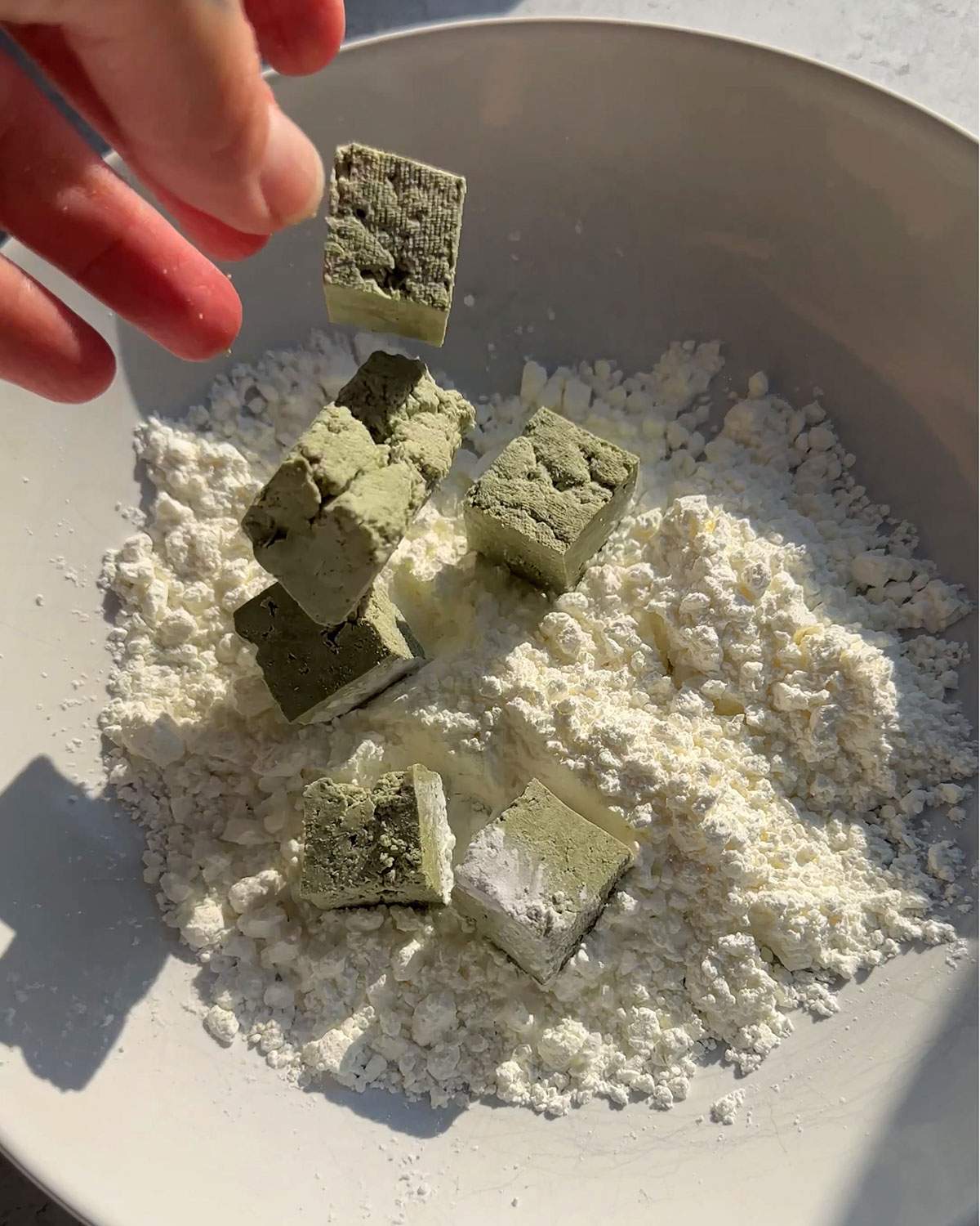 Dropping pumfu cubes into cornstarch to coat.
