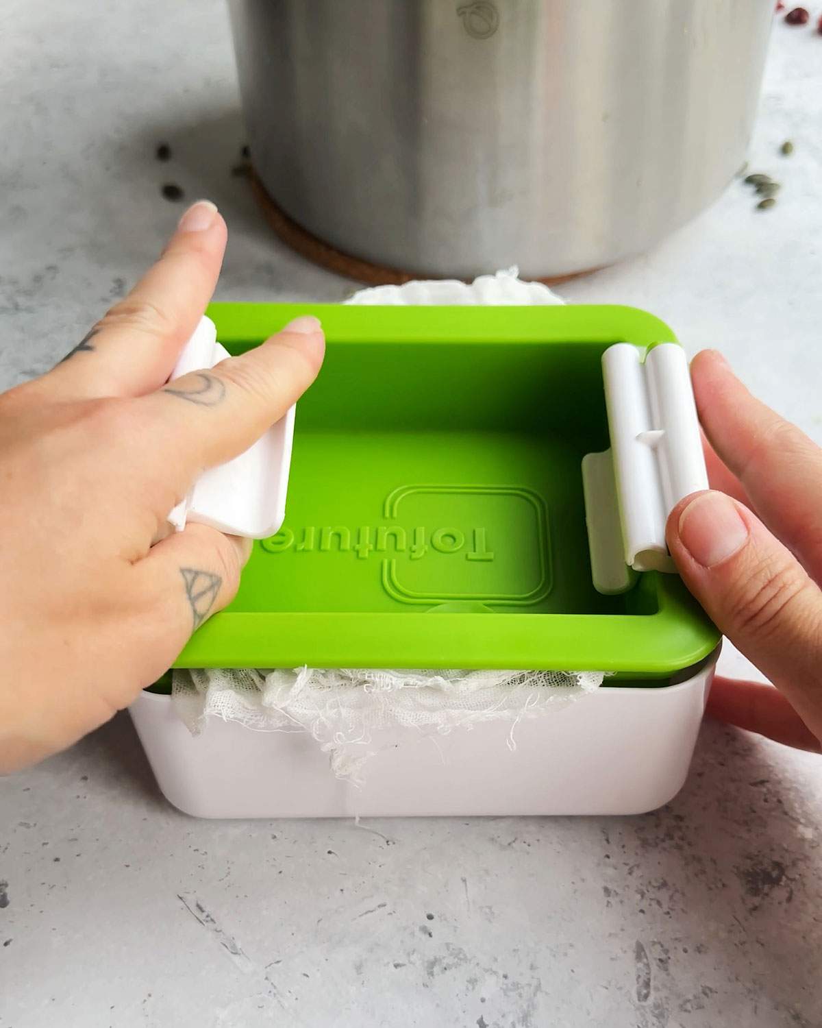 Hand holding a tofu press.