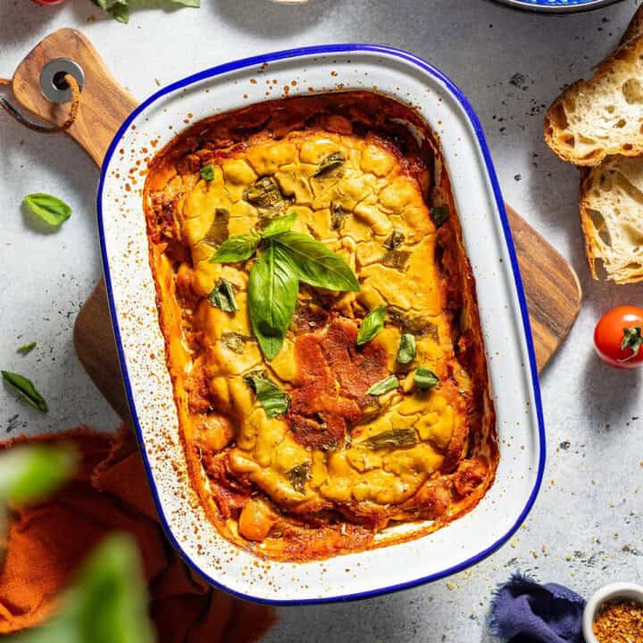 Baked butter beans in a dish on the dinner table, surrounded by ingredients.