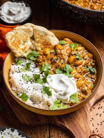 Creamy cutter bean curry in a bowl with rice and naan bread.