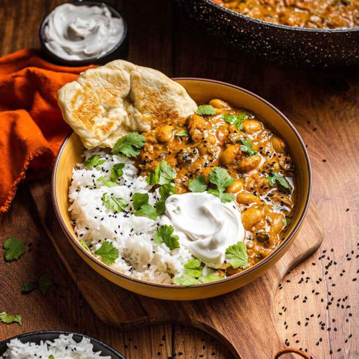 Creamy cutter bean curry in a bowl with rice and naan bread.