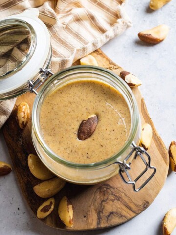 Brazil nut butter in a glass jar on a wooden tray.