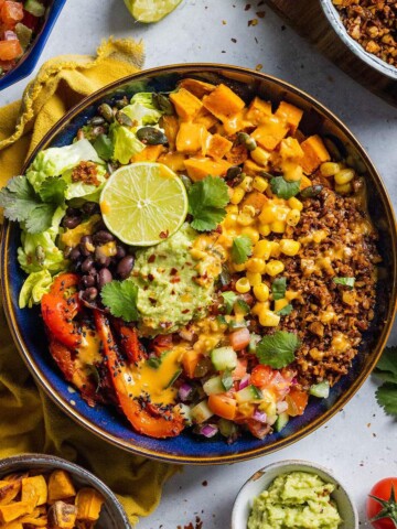 Vegan burrito bowl loaded with vegetables, walnut mince and guacamole on the dinner table.