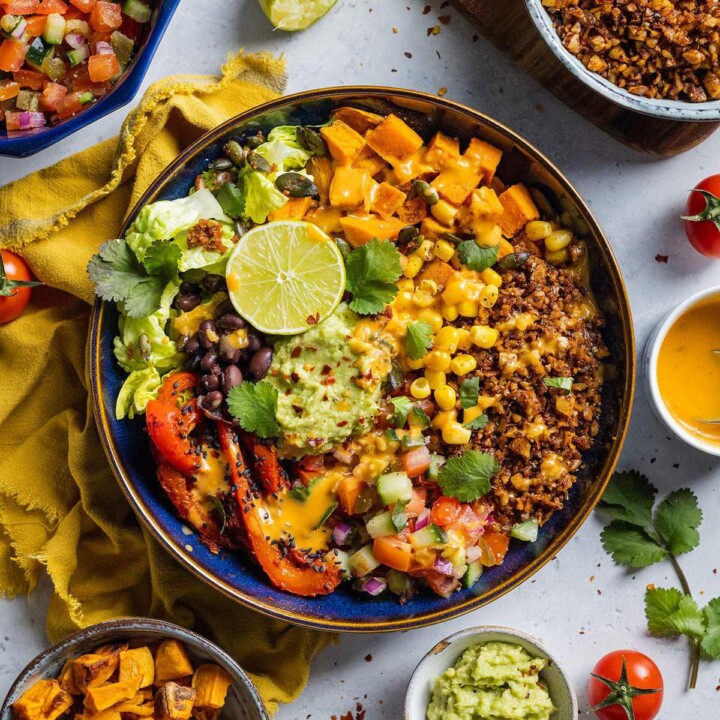 Vegan burrito bowl loaded with vegetables, walnut mince and guacamole on the dinner table.