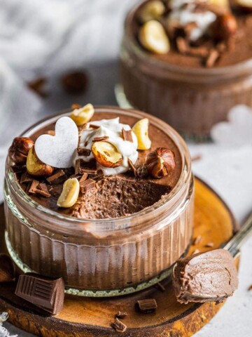 Creamy chocolate mousse in a ramekin with a spoon next to it.