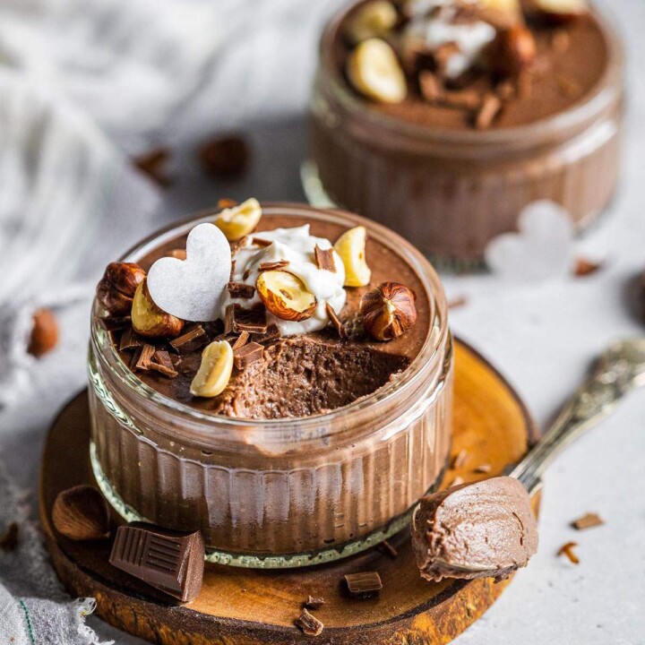 Creamy chocolate mousse in a ramekin with a spoon next to it.