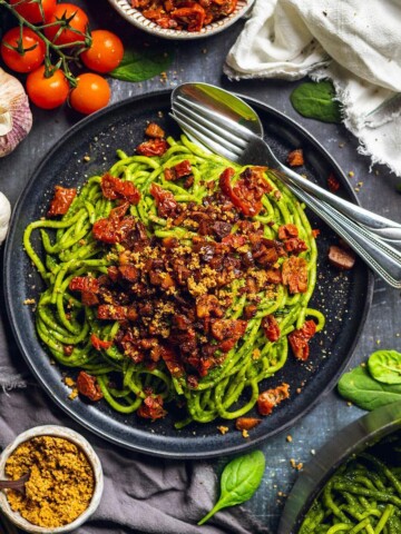 A plate of pasta verde with sun dried tomatoes and smoked tofu on the dinner table.