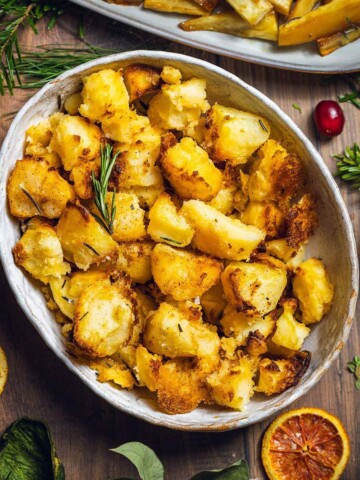 Vegan Roast potatoes in a serving dish on the dinner table.