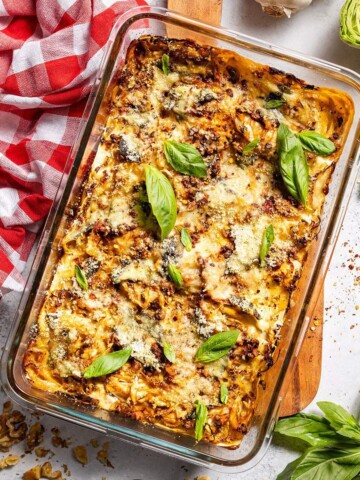Freshly baked vegan cabbage lasagna in an oven dish surrounded by ingredients.