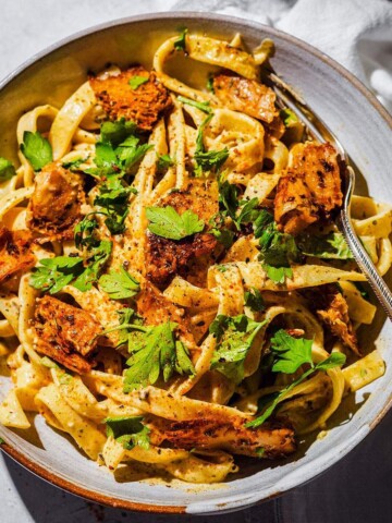 Creamy cajun alfredo with vegan cajun chicken pieces in a pasta bowl.